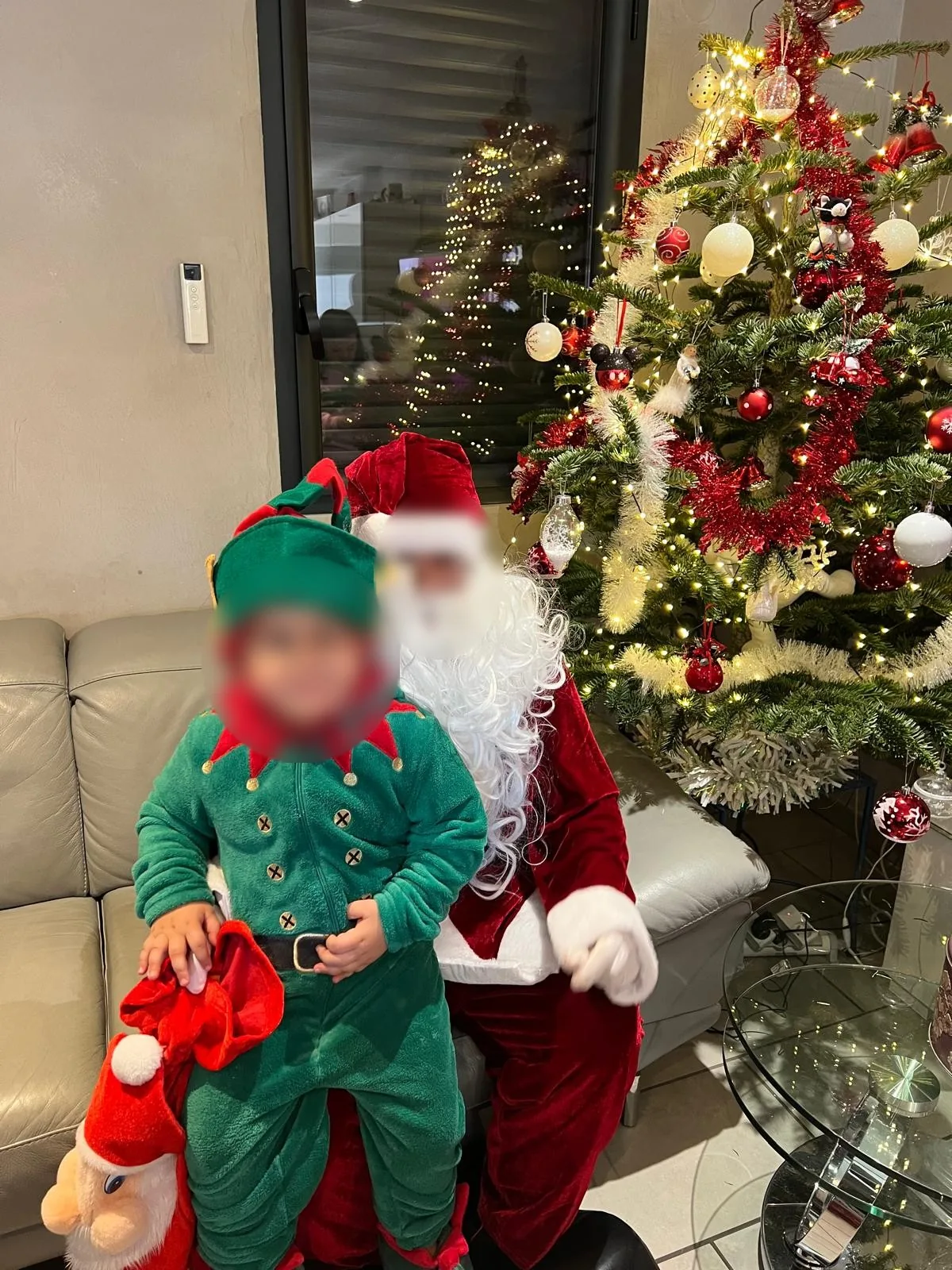 Le Père Noël et un enfant déguisé en lutin devant le sapin
